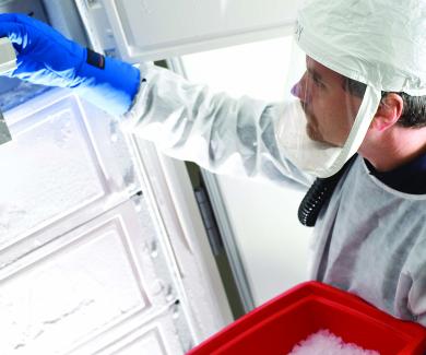 Andy Pekosz, in hazmat gear, removes a sample from a freezer