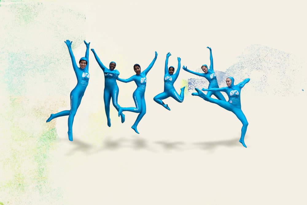 6 students wearing blue full-body spandex suits, leaping into the air