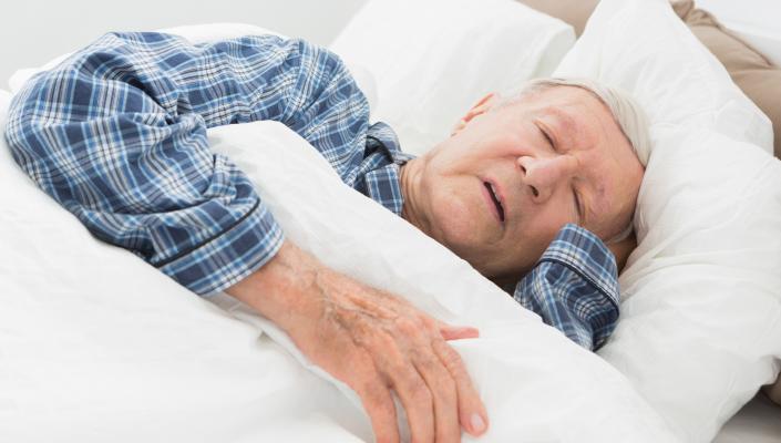 an older adult man asleep with one hand under his head