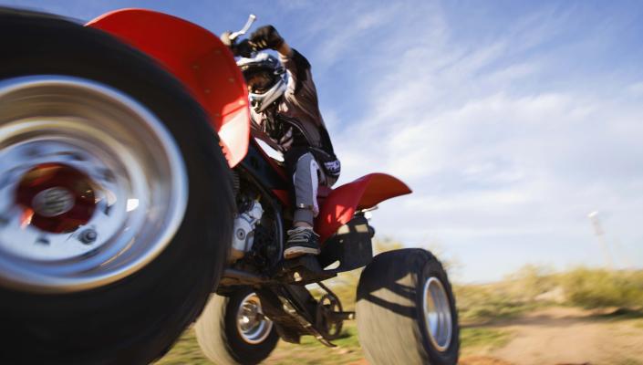 photo of a young person wearing a helmet and riding an airborne ATV