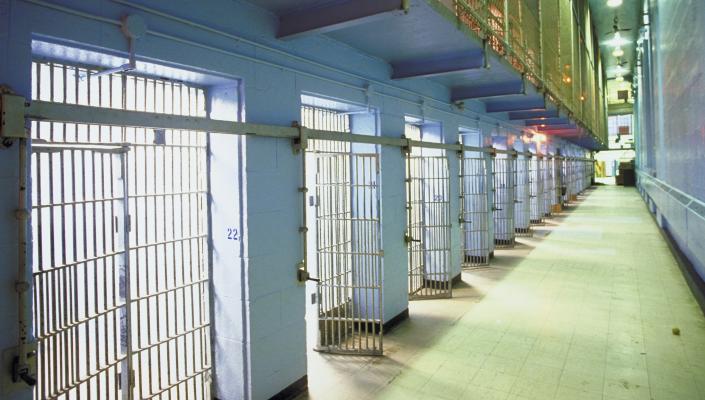 an interior photo of a jail, looking down a long row of cells