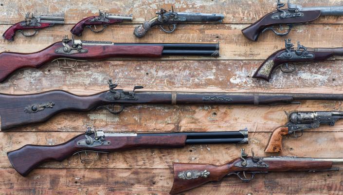 an array of antique handguns and long guns