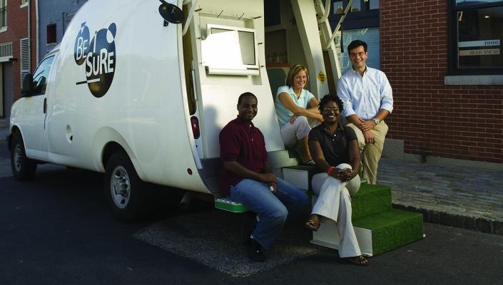 McCay Morifay, Martha Hilton, Frangiscos Sifakis, and Keba Robinson sit and stand at the back of the BESURE van.