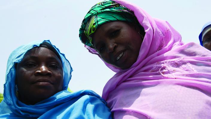 2 Nigerian women, one in a blue scarf and the other in pink