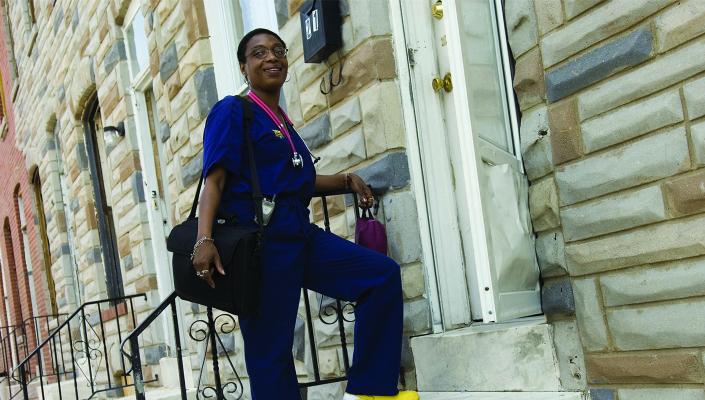 Community health worker Paige Bailey stands on the stoop of a Baltimore rowhome