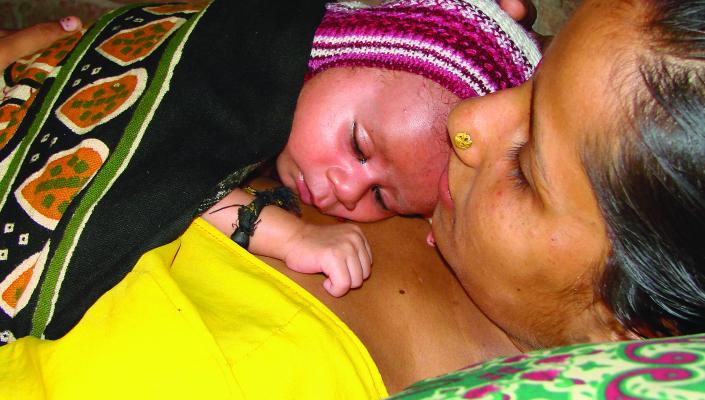 A mother holds her newborn to her chest for skin-to-skin contact