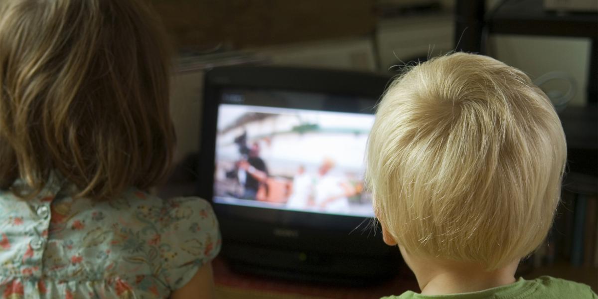 Image from behind of two kids watching television