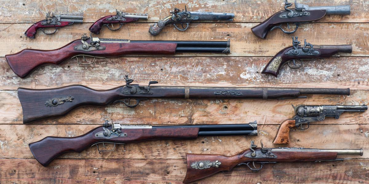 an array of antique handguns and long guns