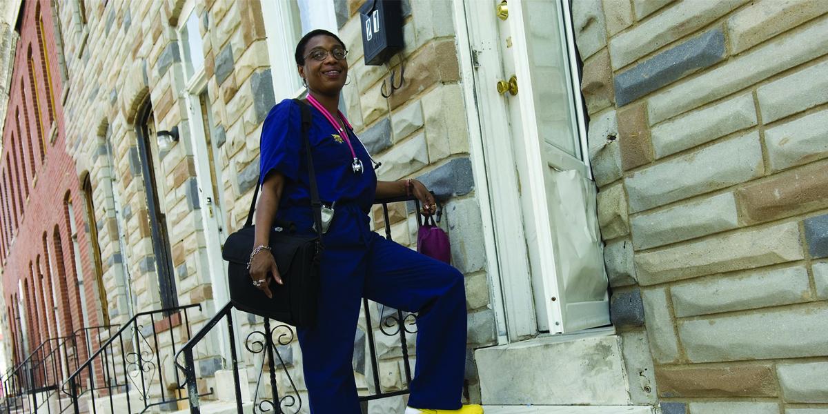 Community health worker Paige Bailey stands on the stoop of a Baltimore rowhome