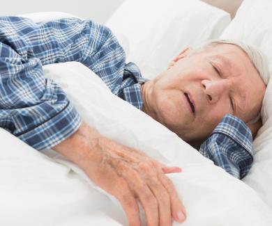 an older adult man asleep with one hand under his head