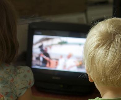 Image from behind of two kids watching television