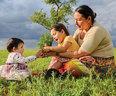 Red Lake Band of Chippewa  member Vernelle Lussier sits with daughters Brielle (left) and Zoie Chaboyea beside Red Lake in Minnesota in June 2022.