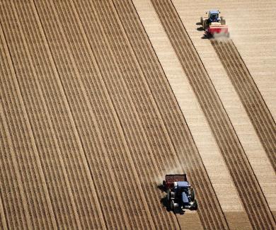 Aerial view of 2 tractors planting potatoes in the fertile farm fields of Idaho, during the spring.