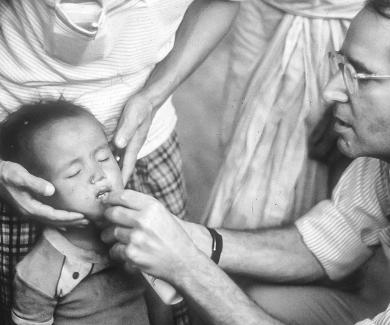 Al Sommer administers the contents of a vitamin A capsule in Nepal’s national vitamin A distribution campaign, c. 1985.